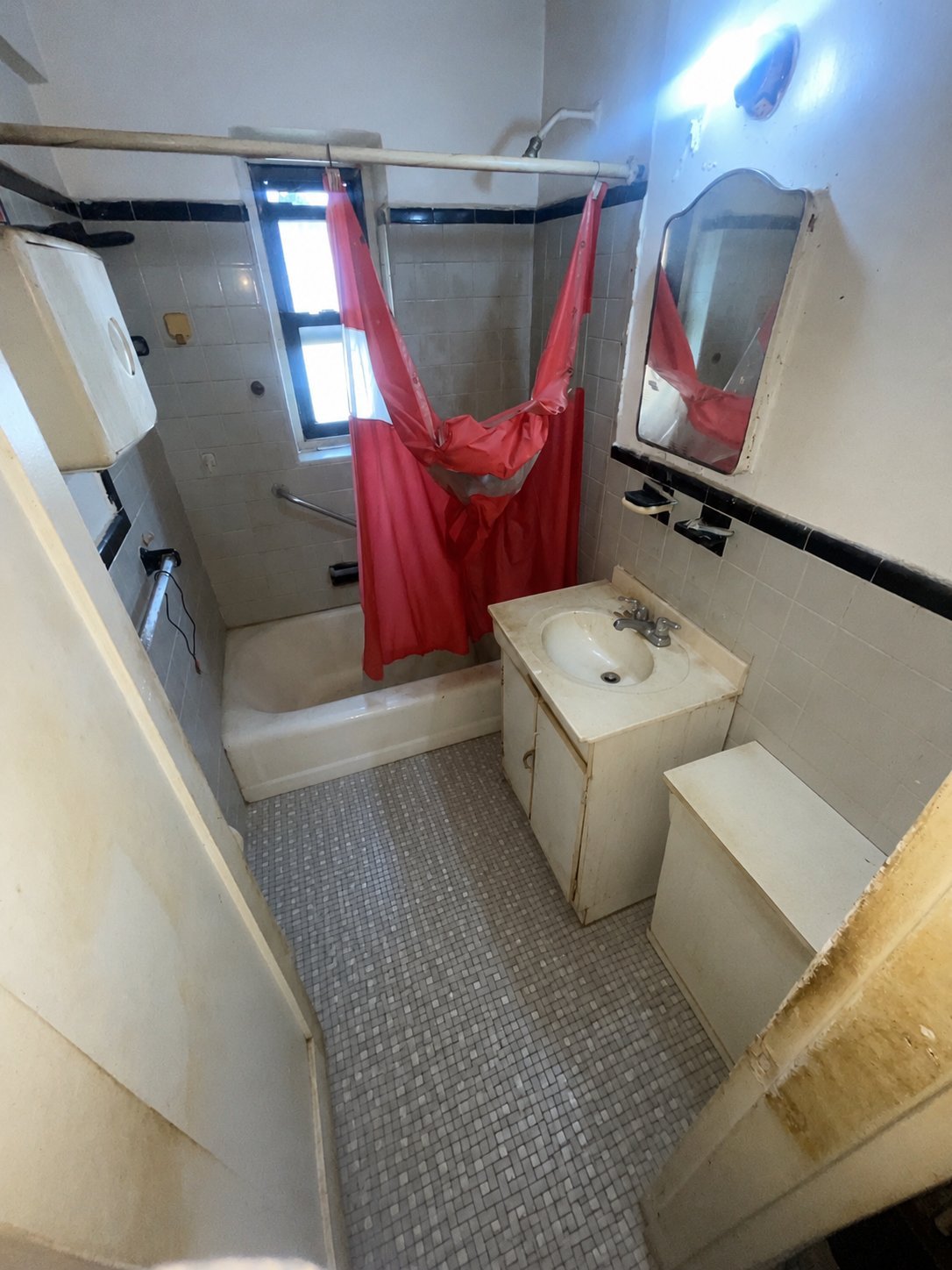 Small residential bathroom with white tile walls, tiled floor, pedestal sink, toilet, and bathtub with red shower curtain